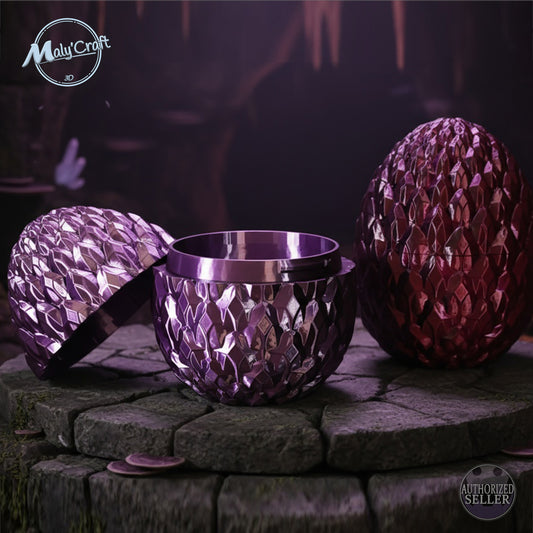 Boîte œuf de dragon 3D Maly’Craft, modèle violet ouvrant effet métal. Design écaille fantasy, idéale comme coffret ou décoration magique. Photo ambiance grotte aux reflets violets et rouges.