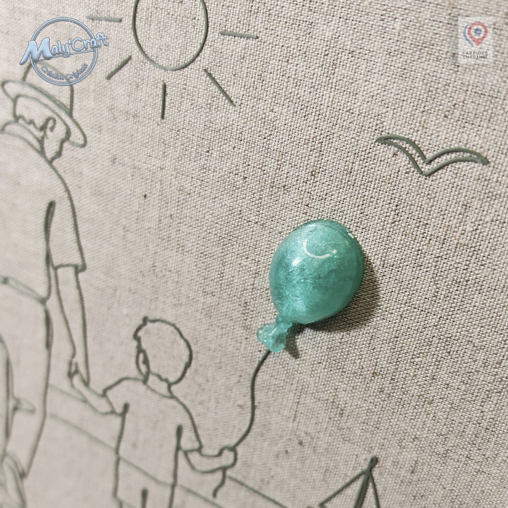 Peut inclure: Un panneau en tissu beige texturé présentant un dessin au trait gris foncé représentant un adulte et un enfant marchant ensemble. Un ballon tridimensionnel vert menthe brillant est fixé au tissu, relié à la main de l'enfant par un trait fin.