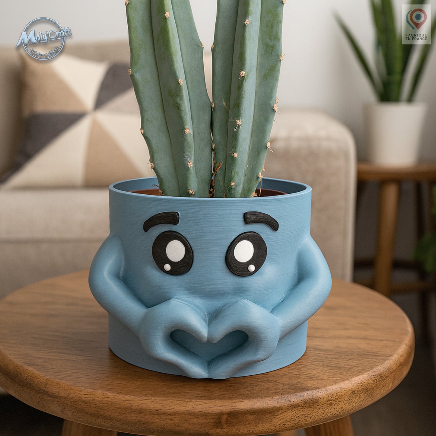 Cache-pot décoratif imprimé en 3D en forme de visage bleu avec de grands yeux expressifs et des bras formant un cœur. Design moderne et original, idéal pour apporter une touche de fantaisie et de tendresse à une décoration intérieure. Fabriqué en France, parfait pour accueillir des plantes vertes ou cactus et offrir un cadeau unique et symbolique.