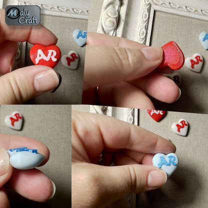 Gros plan sur des cœurs personnalisés imprimés en 3D, avec initiales en relief et aperçu du verso aimanté.