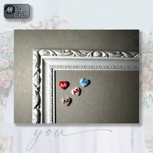 Lot de petits cœurs personnalisés en 3D avec initiales, posés sur un fond textile beige encadré, parfaits comme cadeaux d'invités de mariage.