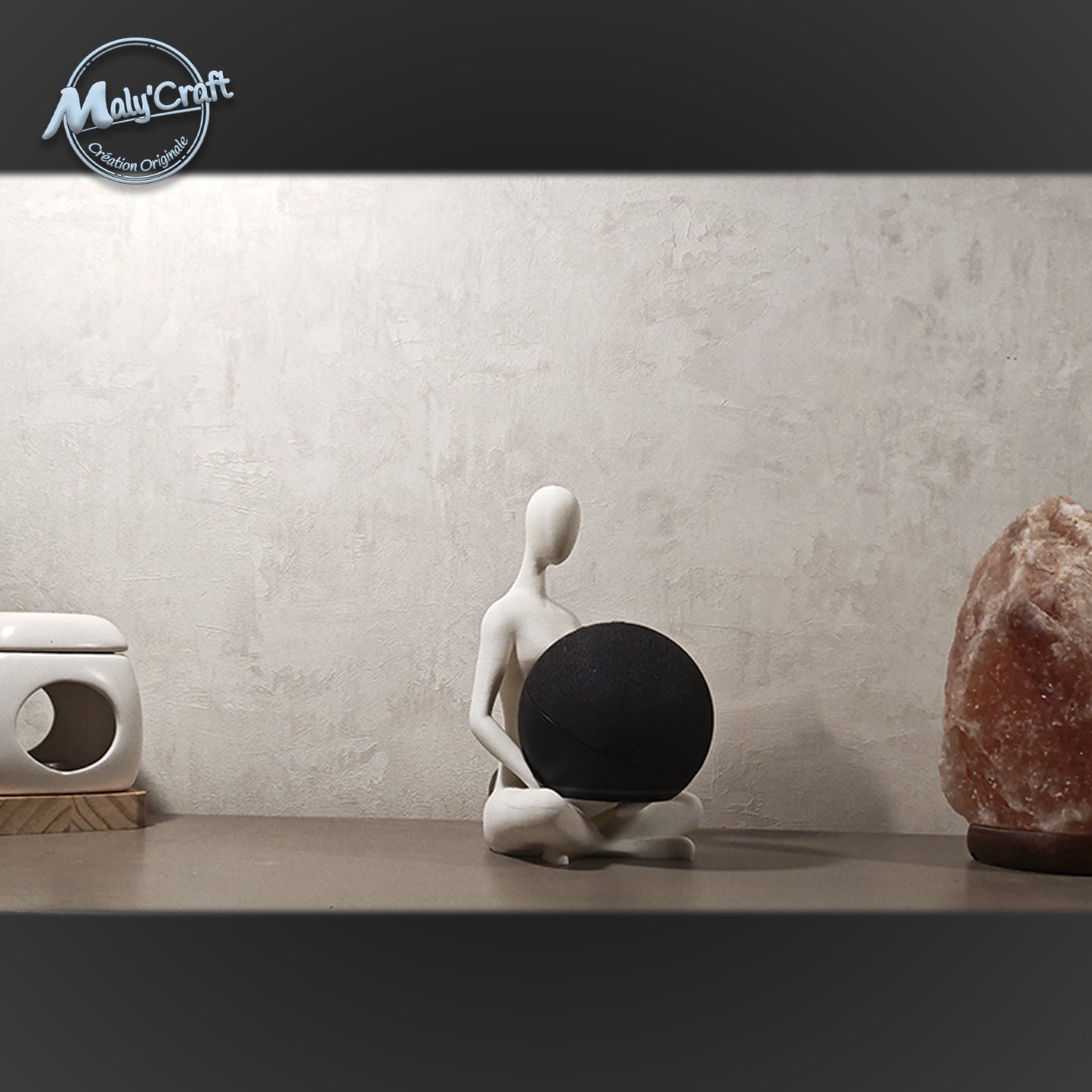 Support Alexa Echo Dot imprimé en 3D, figurine minimaliste assise en lotus, posé sur un meuble entre une lampe de sel et un diffuseur. Design zen et moderne, fabriqué en France. 3D printed Echo Dot stand, minimalist figurine in lotus pose, placed on a shelf between a salt lamp and an oil burner. Zen and modern design, handmade in France.