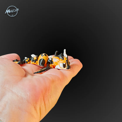 Dragon articulé Halloween orange et noir tenu dans la paume de la main, montrant sa petite taille et ses détails en 3D.