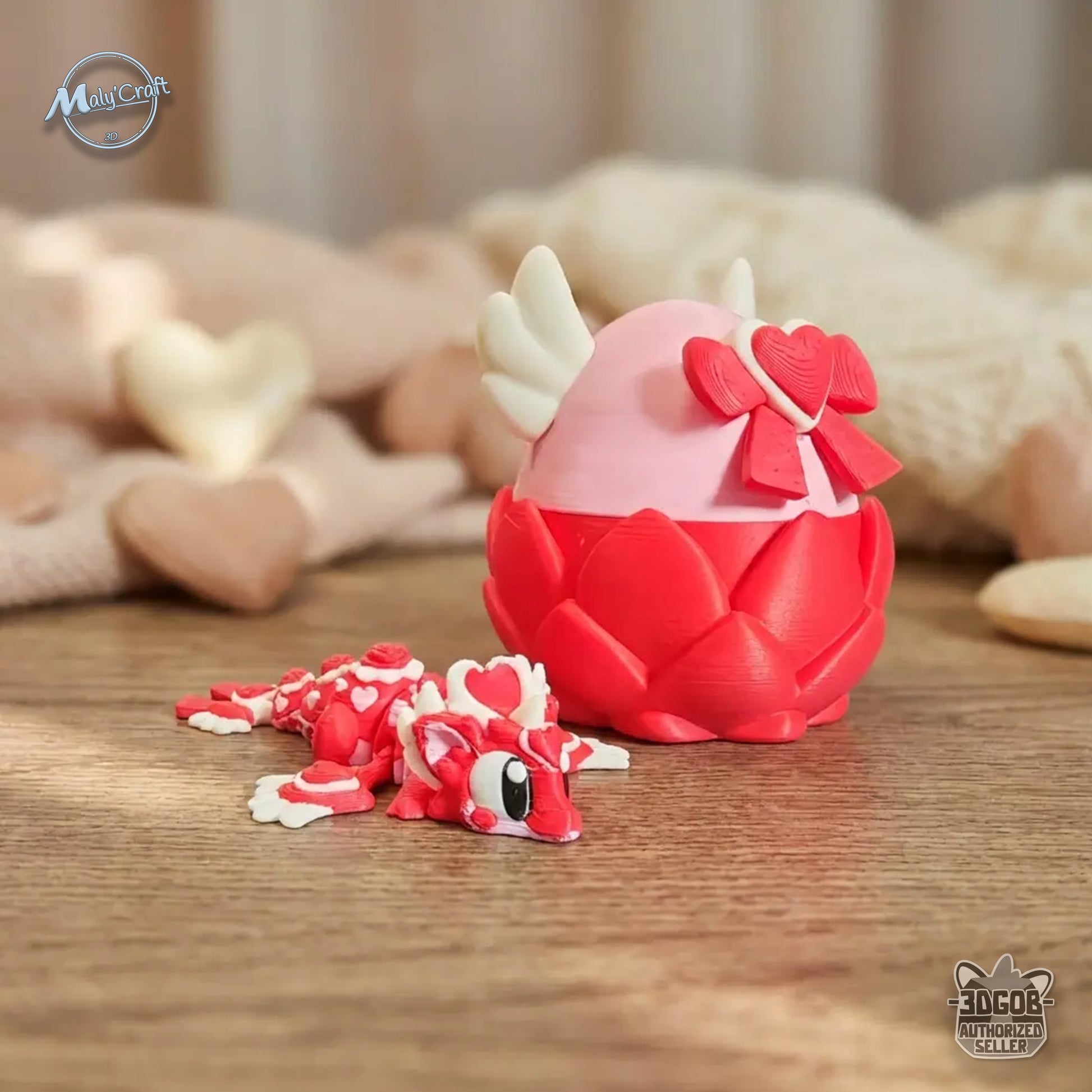 Figurine dragon articulé rouge et blanc avec détails de cœurs sur le corps, création éco-responsable en amidon de maïs. Il est présenté à coté de son oeuf ouvrable