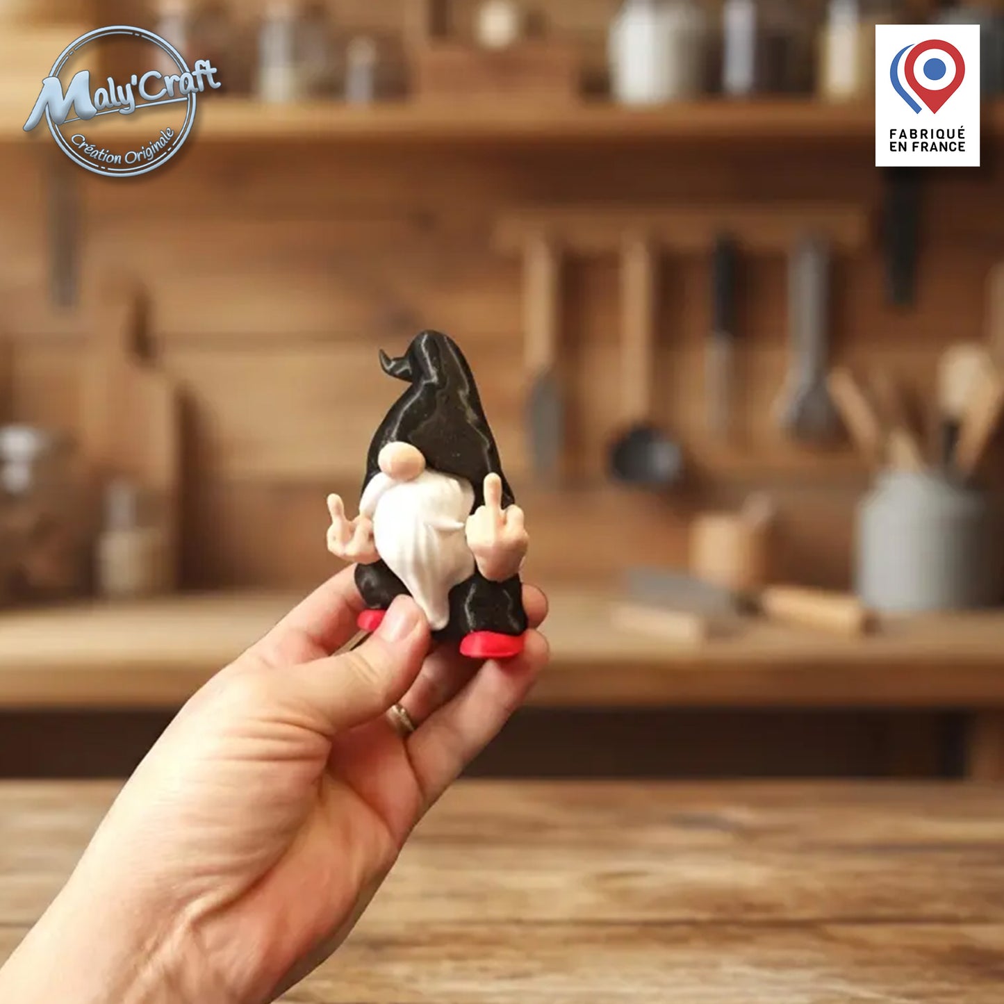 Figurine de gnome rebelle de 9 cm tenue en main pour illustrer sa taille réelle. Ce modèle insolite effectue un double doigt d'honneur avec un sens du détail unique. Création originale modélisée et imprimée en 3D de précision en France dans mon atelier. La figurine présente une robe noire mate, une barbe blanche sculptée et des chaussures rouges. Conçue avec des filaments de marques premium (Panchroma, Polymaker), elle est disponible en couleurs personnalisables ou en version couleur unie.
