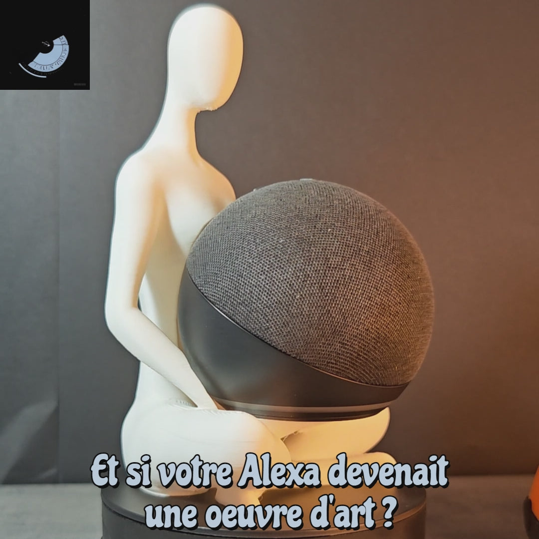 Vidéo montrant un support Alexa Echo Dot Maly’Craft en forme de silhouette blanche assise, tenant l’enceinte connectée noire. Fond gris chaud et phrase “Et si votre Alexa devenait une œuvre d’art ?” affichée à l’écran.