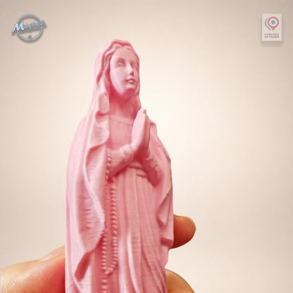 Gros plan sur les mains jointes en prière d'une statue Vierge Marie rose en impression 3D, tenue entre les doigts pour montrer l'échelle
Close up of the praying hands of a pink 3D printed Virgin Mary statue, held between fingers to show scale