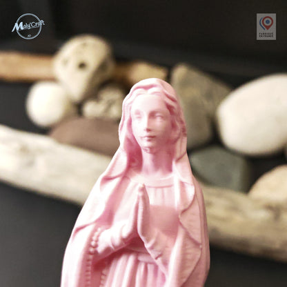 Portrait rapproché du visage d'une statue Vierge Marie rose en impression 3D, décor de galets en arrière-plan
Close up portrait of the face of a pink 3D printed Virgin Mary statue, with pebbles in the background